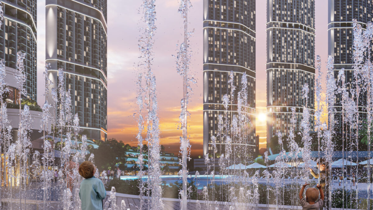 Dancing fountains in front of towering residential buildings with a modern design, illuminated by the warm light of the sunset.