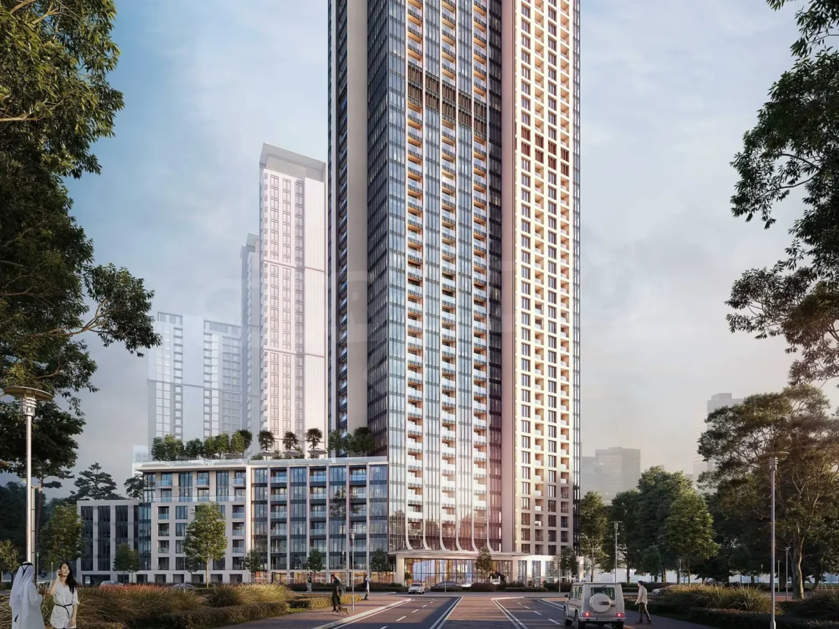 A modern skyscraper with a sleek glass facade, surrounded by landscaped greenery and low-rise residential buildings, under a bright sky.